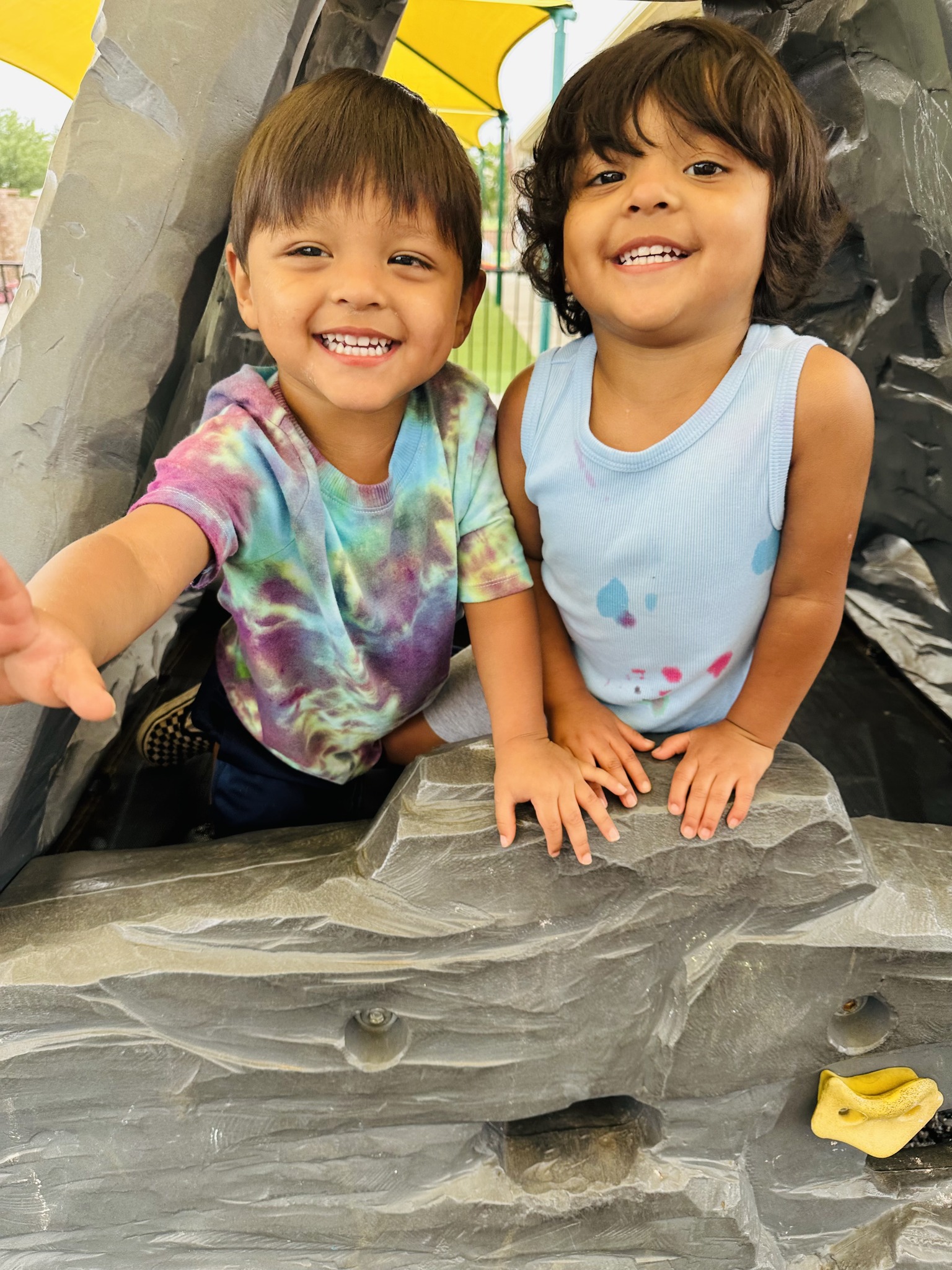 Two children smiling from inside a play structure