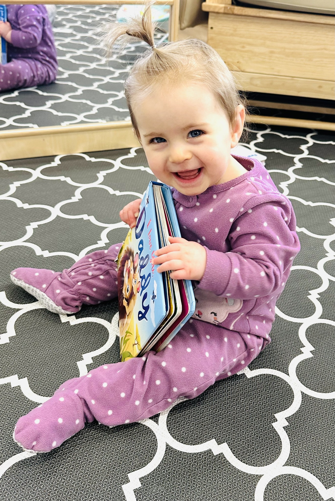 Child sitting on floor holding a book