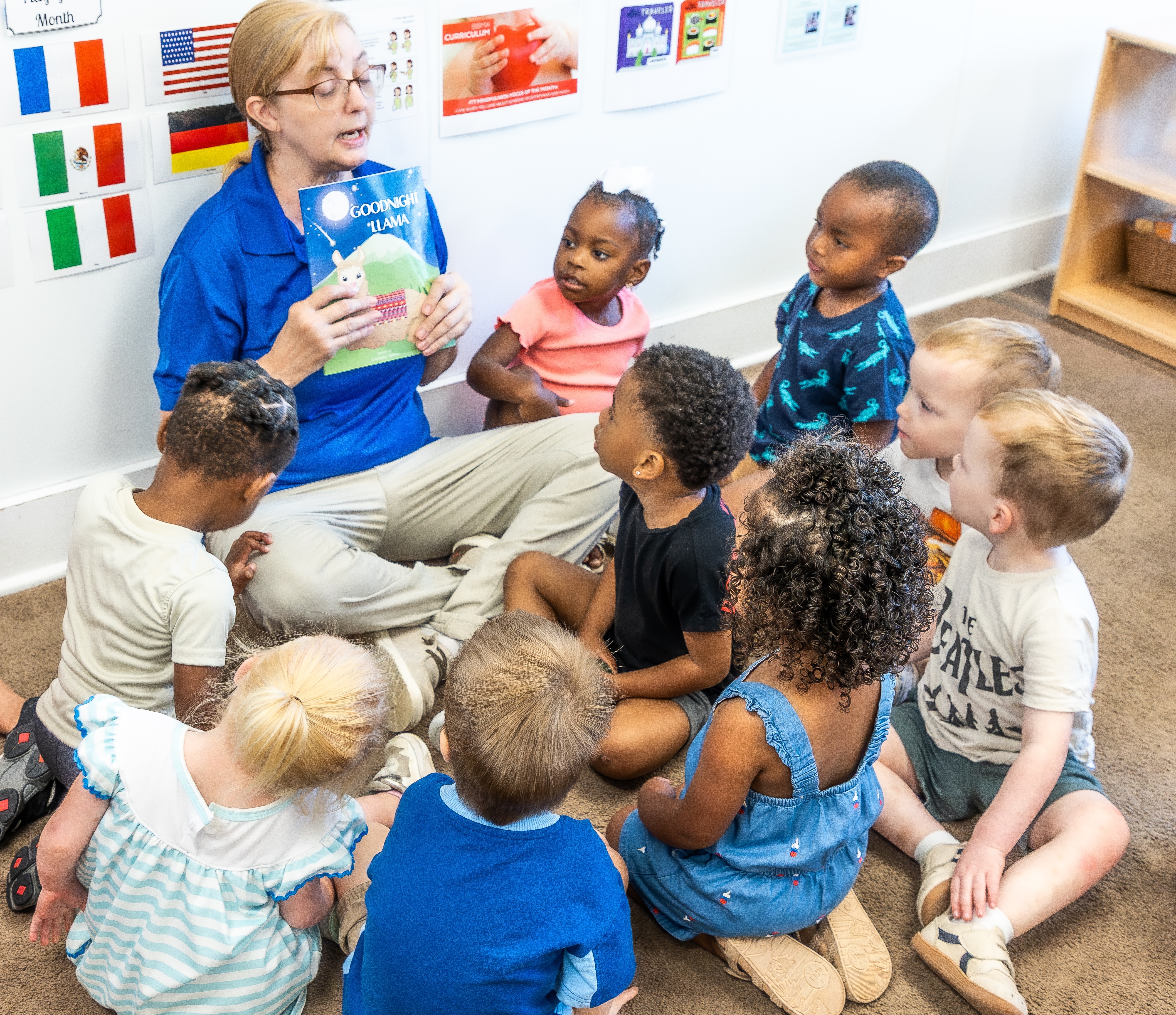 Adult reading a book to a group of children in a classroom