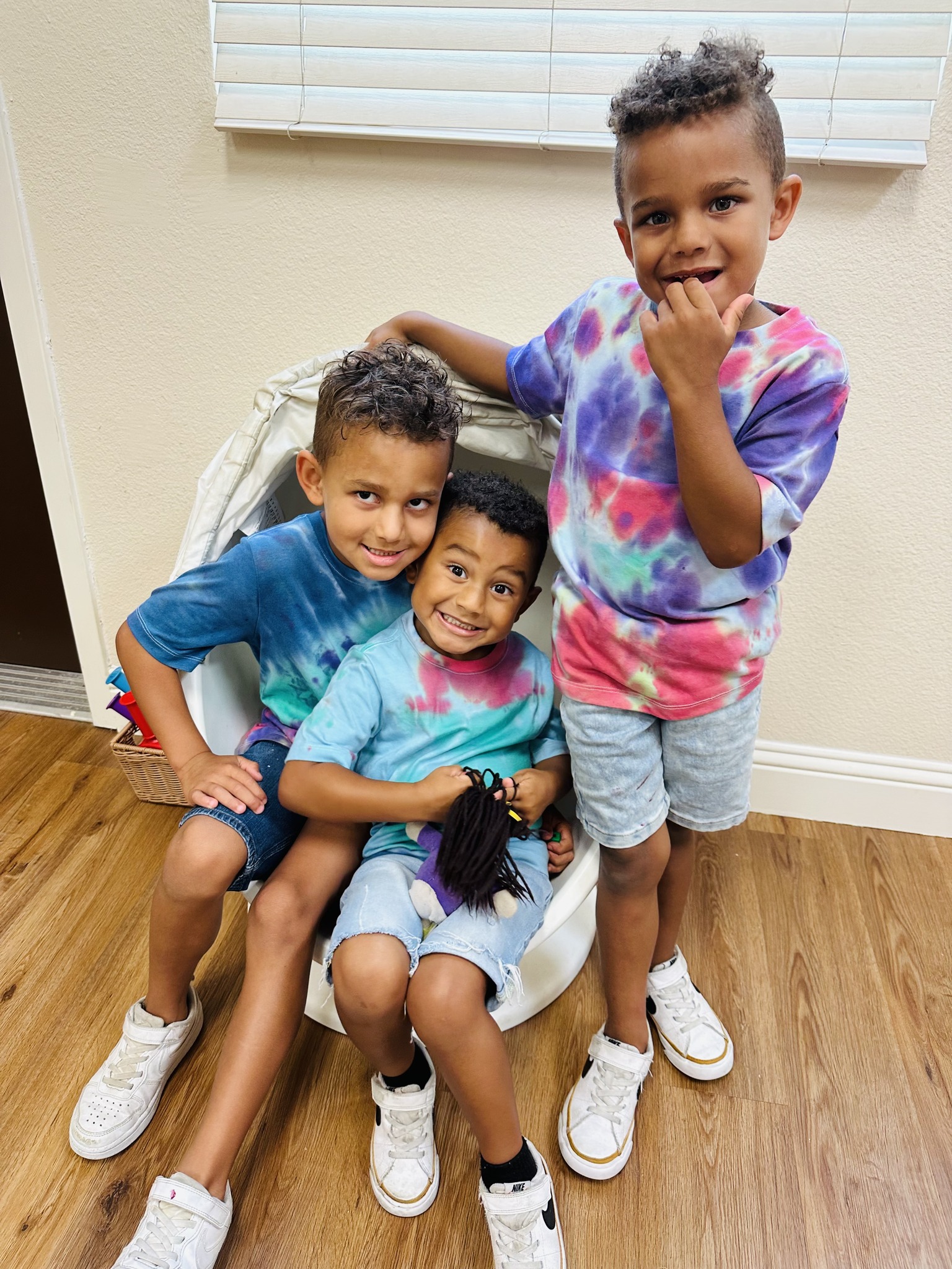 Three children in tie-dye shirts posing together