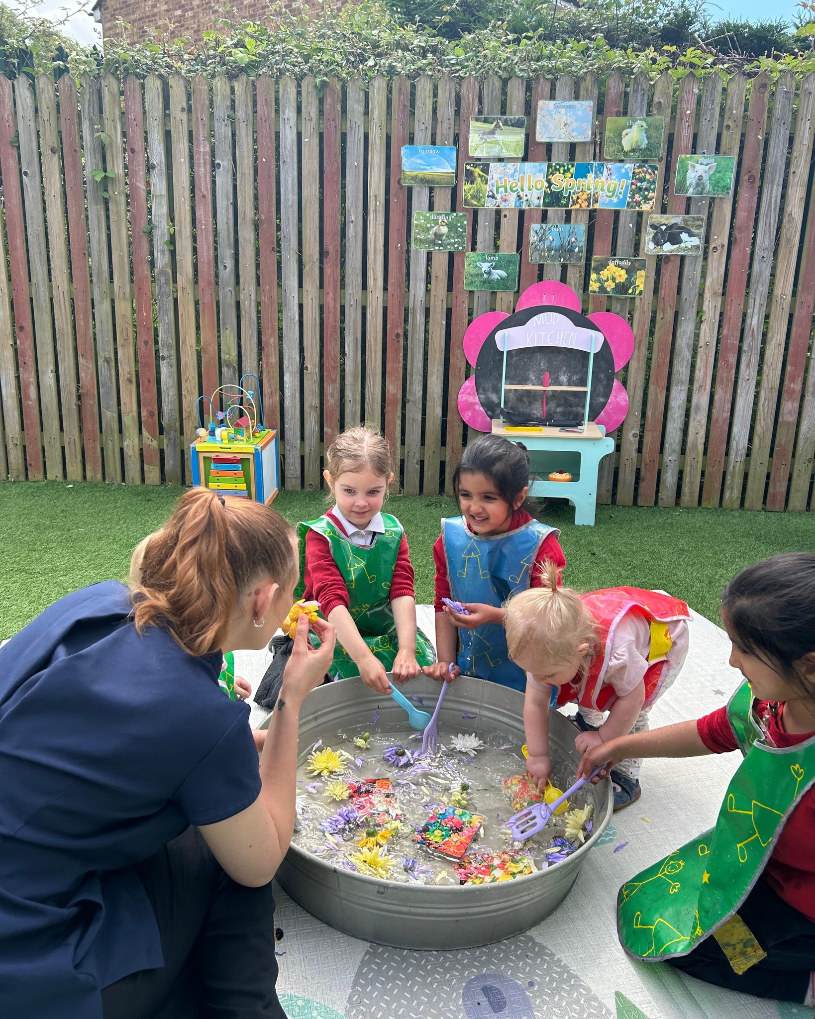 Adult and children playing with water and toys in a large tub outdoors