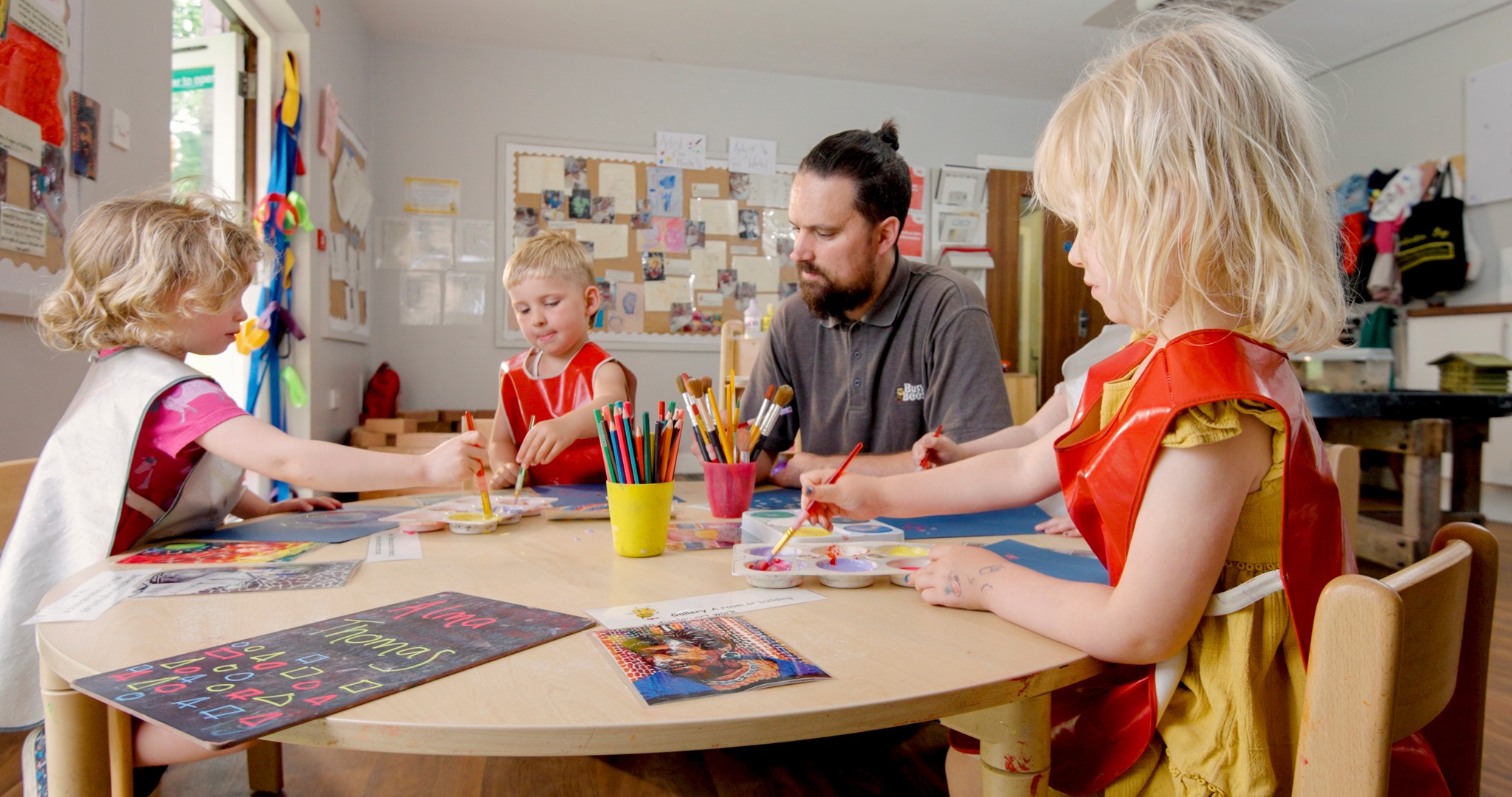Adult and three children painting at a table
