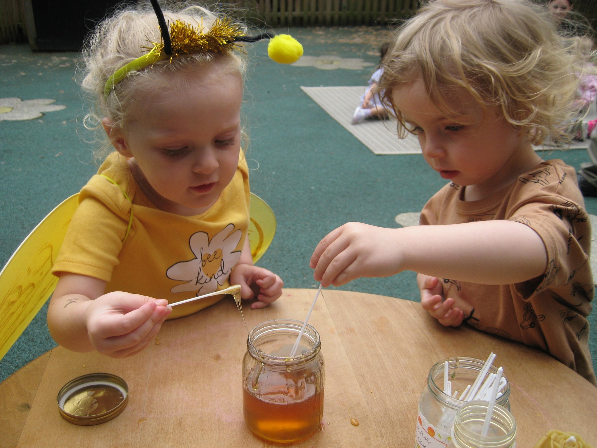 Two children at a table with jars of honey