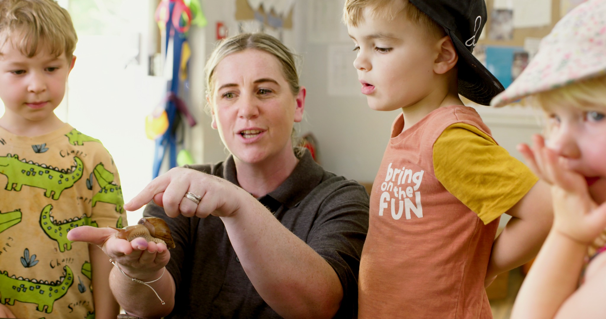 Adult showing small animal to children in a classroom