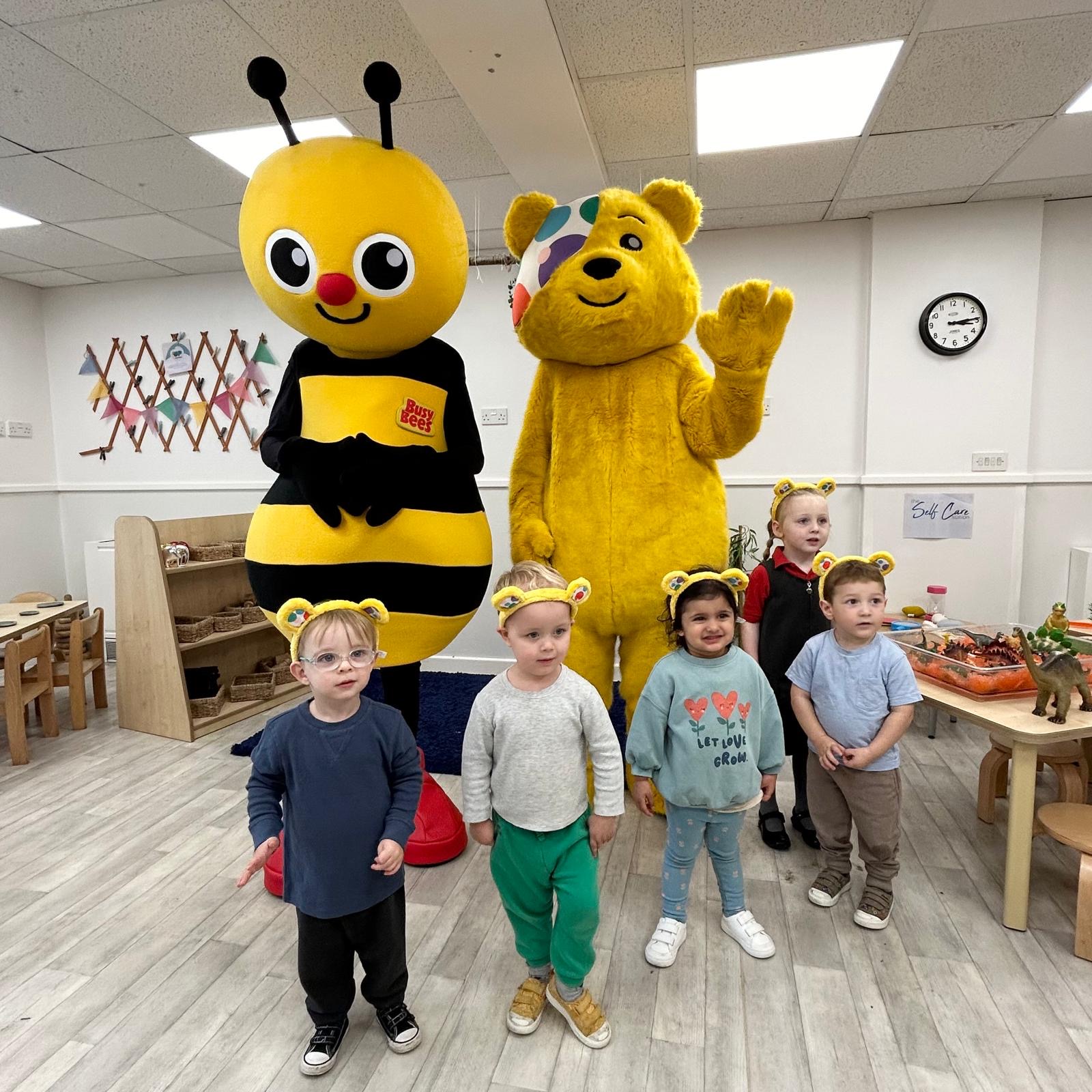 Two people in mascot costumes with five children wearing headbands
