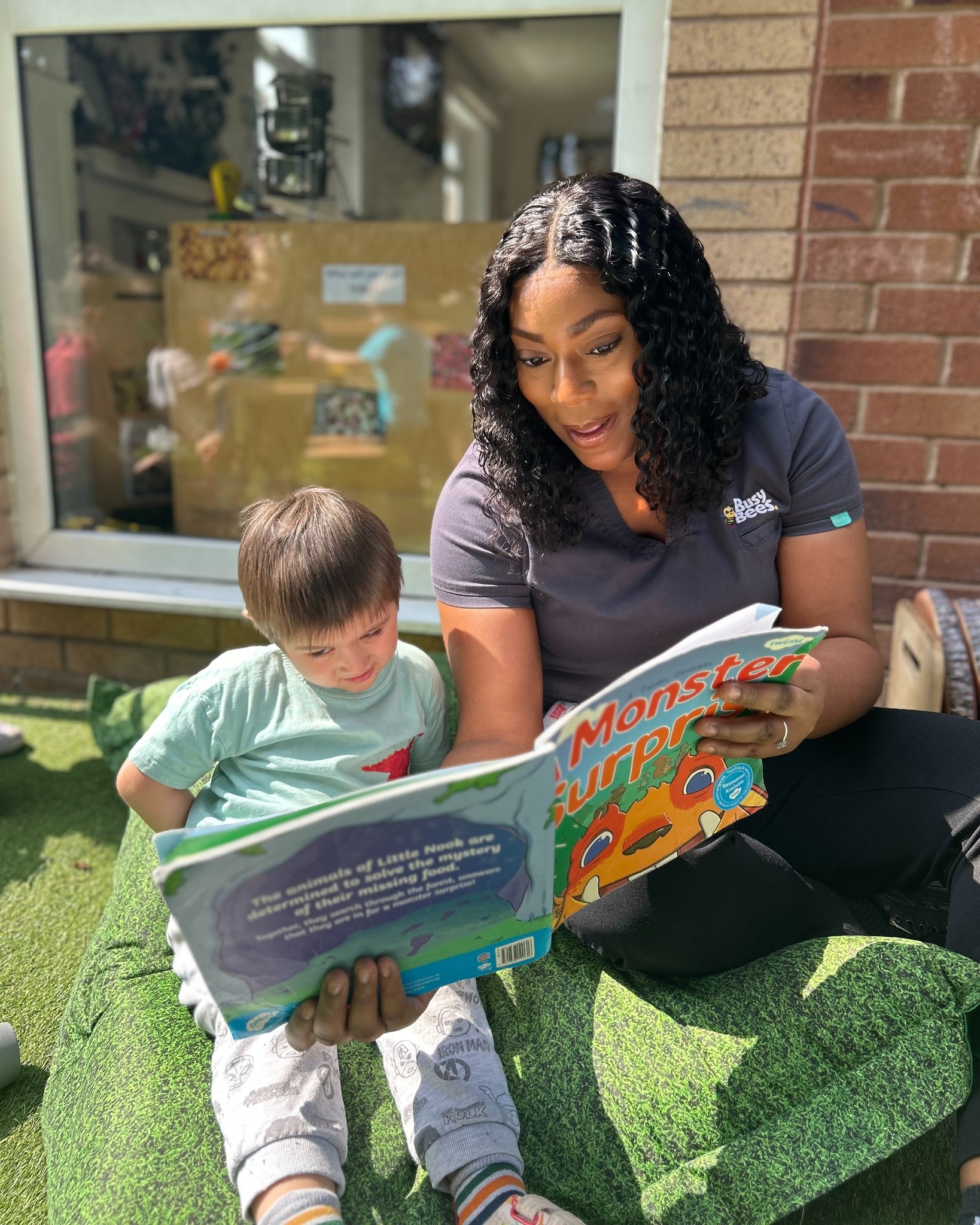 Person and child reading a book together outdoors