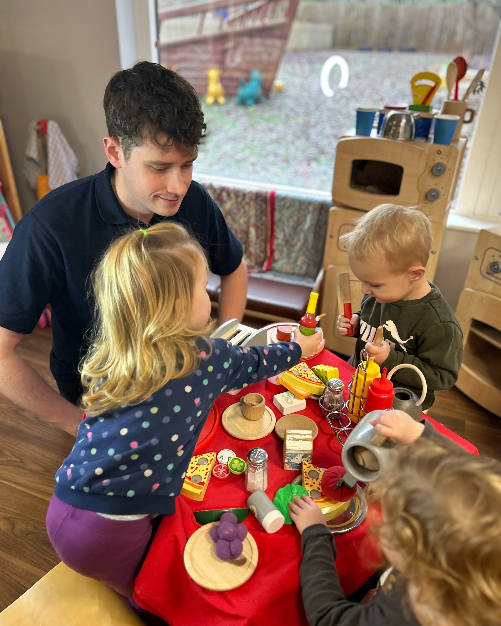 Adult and children playing with toy food at a table