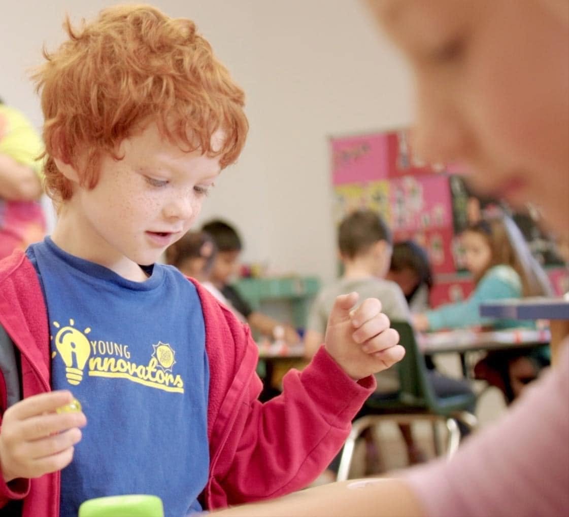 Child wearing a Young Innovators t-shirt participating in a classroom activity