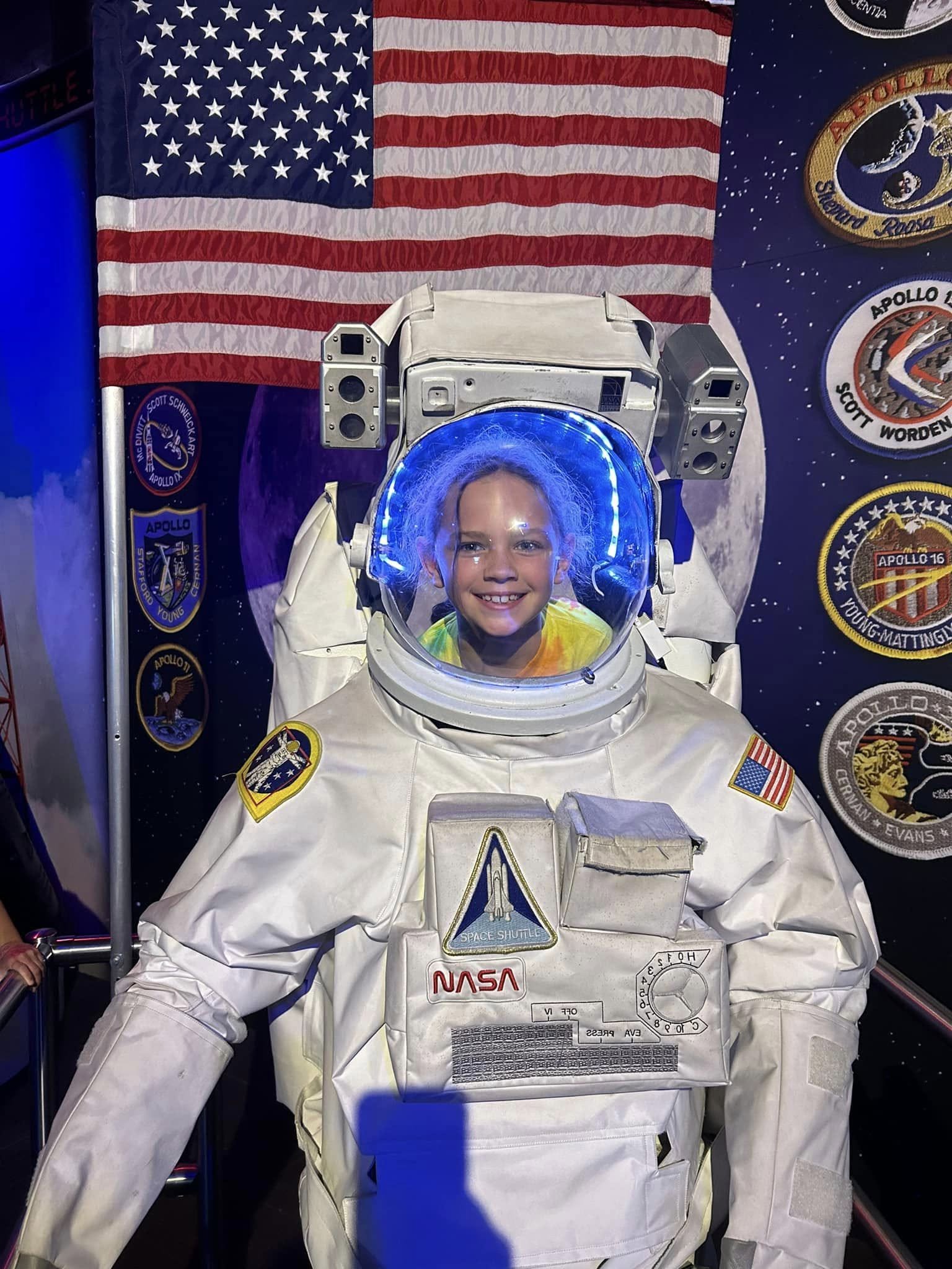 Child wearing an astronaut suit with an American flag background