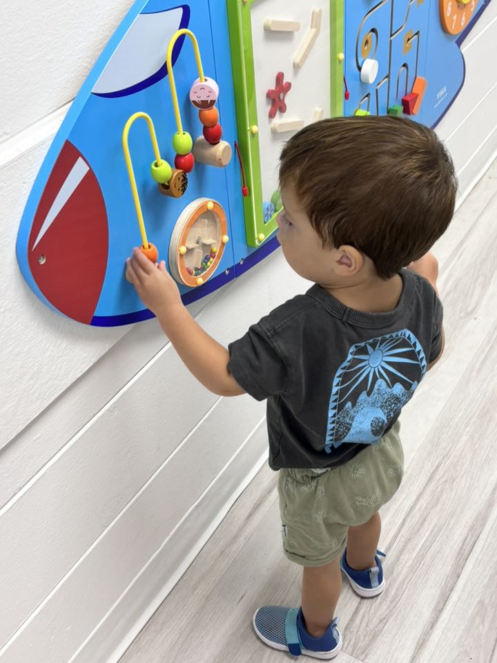 Child playing with a wall-mounted bead maze activity board