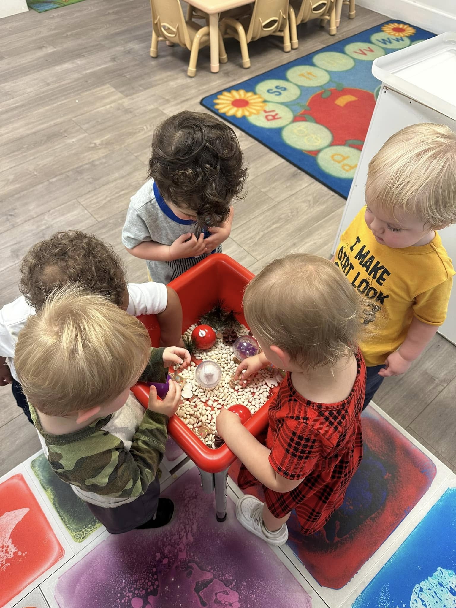 Group of children playing together at a sensory table in a classroom
