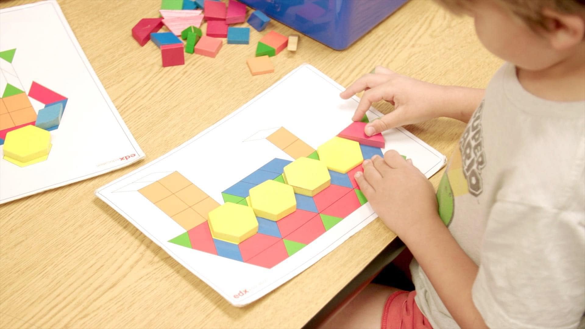Child placing a pattern block on a worksheet