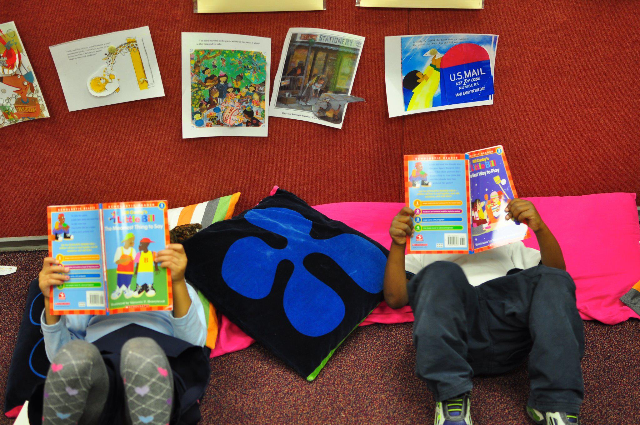 Two children sitting on the floor reading books