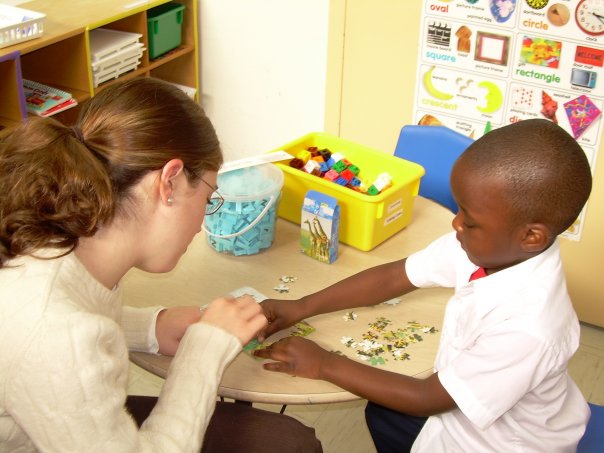 Person and child playing with small objects at a table