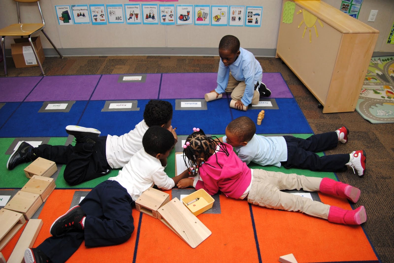 Children playing with blocks on a colorful mat in a classroom