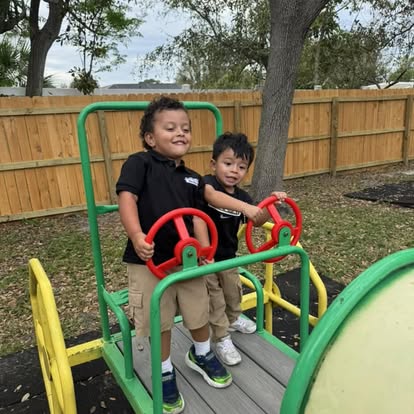 Two children standing and holding steering wheels on a playground structure
