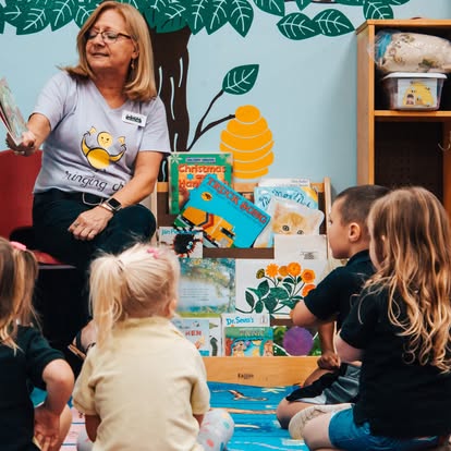 Adult reading a book to a group of children in a classroom