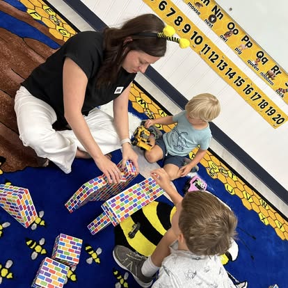 Adult and children playing with building blocks on a classroom rug