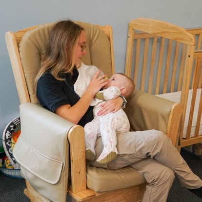 Person holding and bottle feeding a baby in a rocking chair