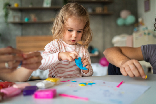 Child playing with blue modeling clay at a table