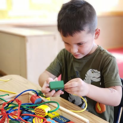 Child playing with lacing beads at a table
