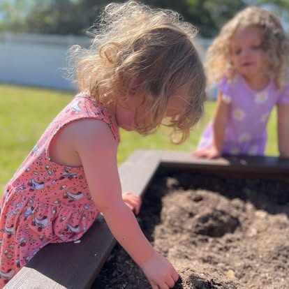 Two children playing in a raised garden bed