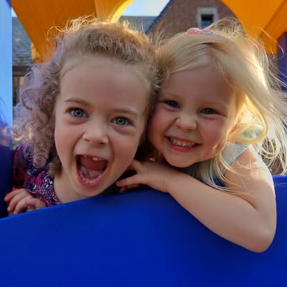 Two children smiling and looking over a blue surface