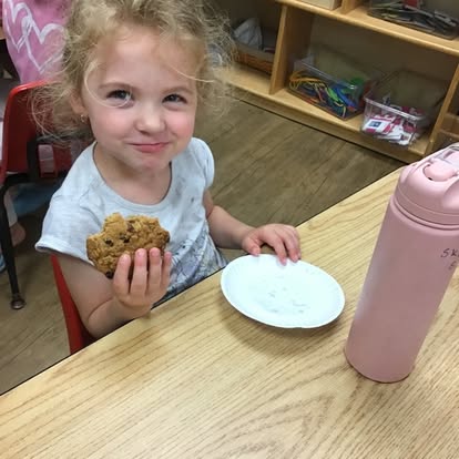 Child holding a cookie at a table