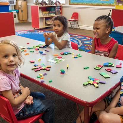 Children playing with colorful blocks at a table in a classroom