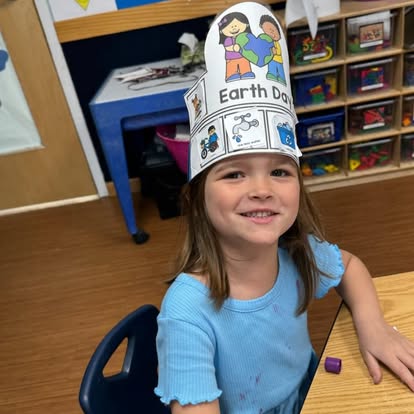 Child wearing a paper hat with "Earth Day" written on it