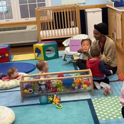 Person reading a book to children in a play area