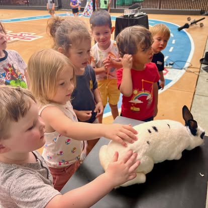 Children petting a white rabbit with black spots