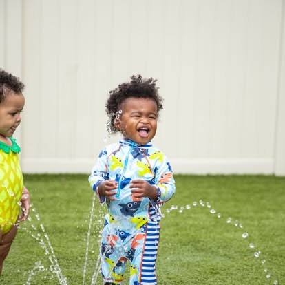 Two children playing in water from of a sprinkler
