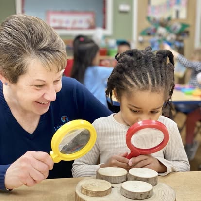 Adult and child looking at wooden discs with magnifying glasses