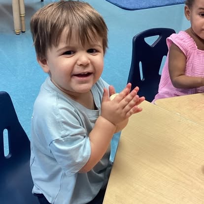 Child at a table with hands together