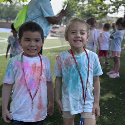 Two children in tie-dye shirts with lanyards around their necks