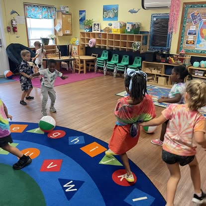 Children playing with a ball on a letter and number rug in a classroom