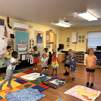Children standing on a colorful rug in a classroom