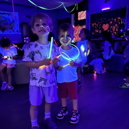 Two children holding glow sticks in a dark room