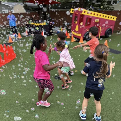 Children playing with bubbles on a green surface