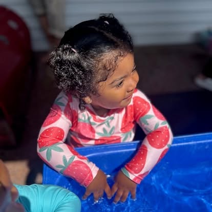 Child in a strawberry-patterned shirt in a blue container
