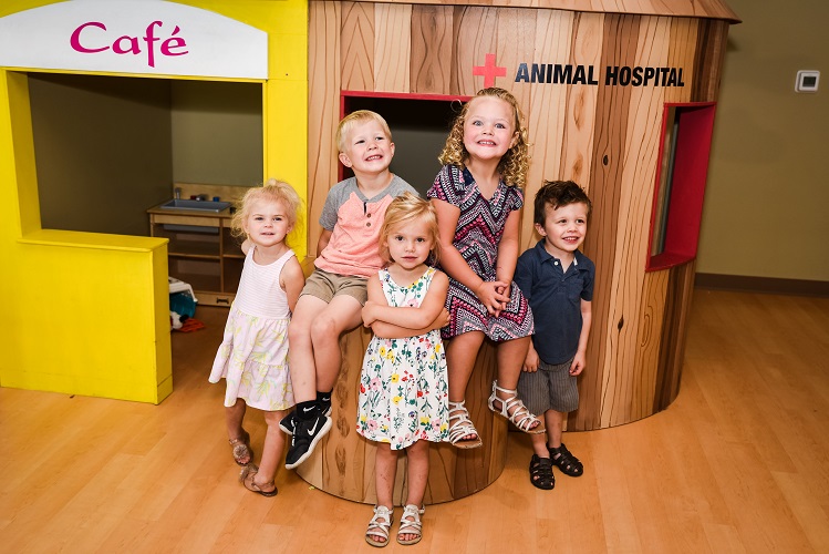 Five children posing in front of a play cafe and animal hospital