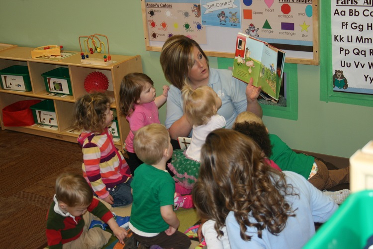 Person reading a book to a group of children in a classroom