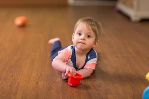 Child lying on floor holding a red toy cup