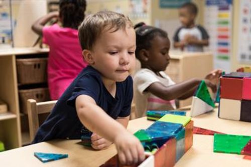 Child playing with colorful magnetic blocks at a table