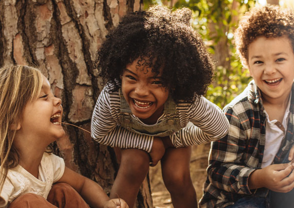 Three children laughing outdoors