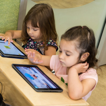 Two children looking at tablets
