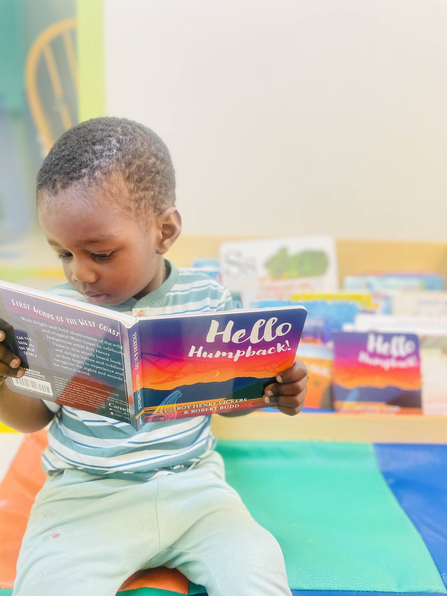 Child reading a book titled "Hello Humpback!"
