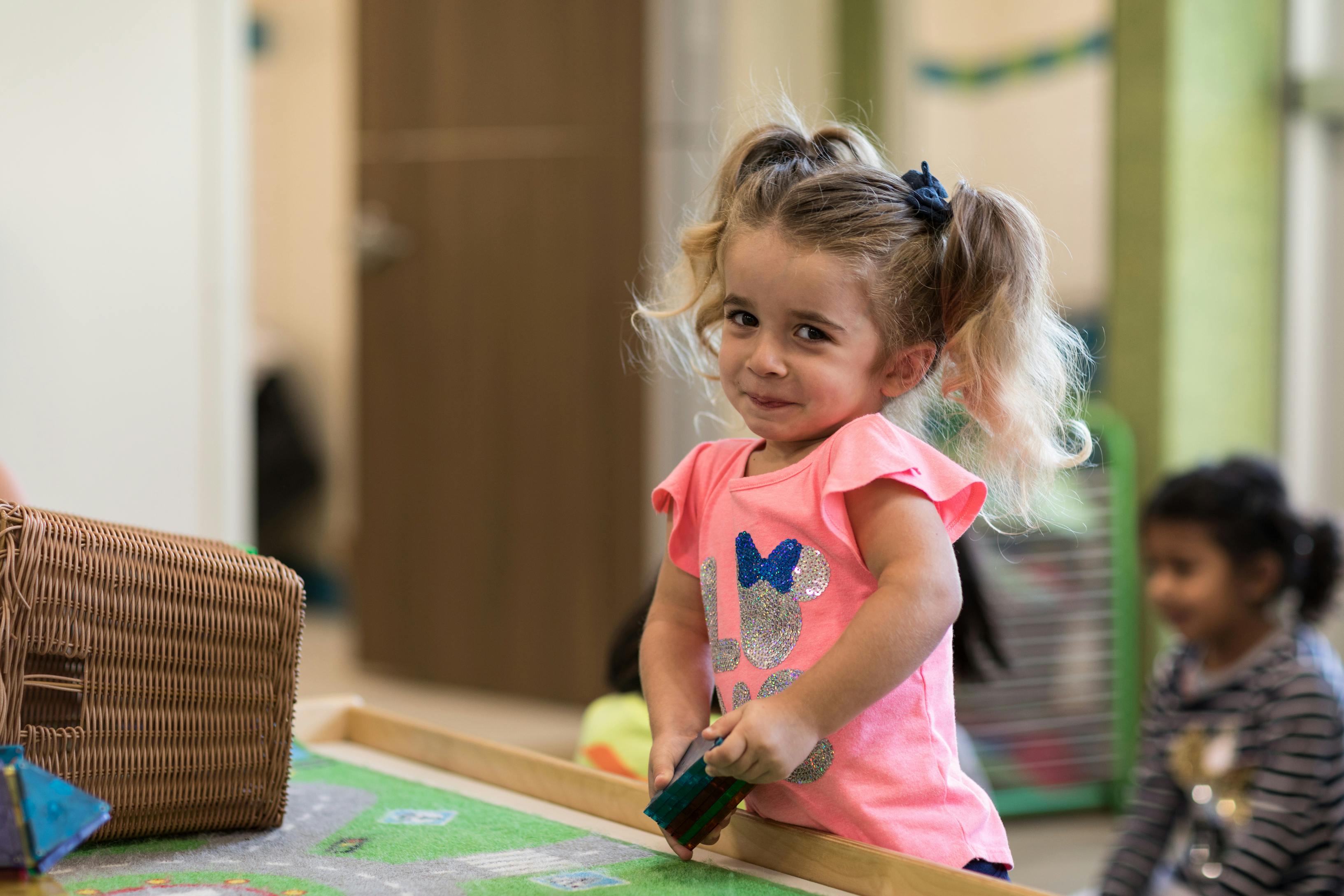 Child with pigtails playing with a toy in a classroom