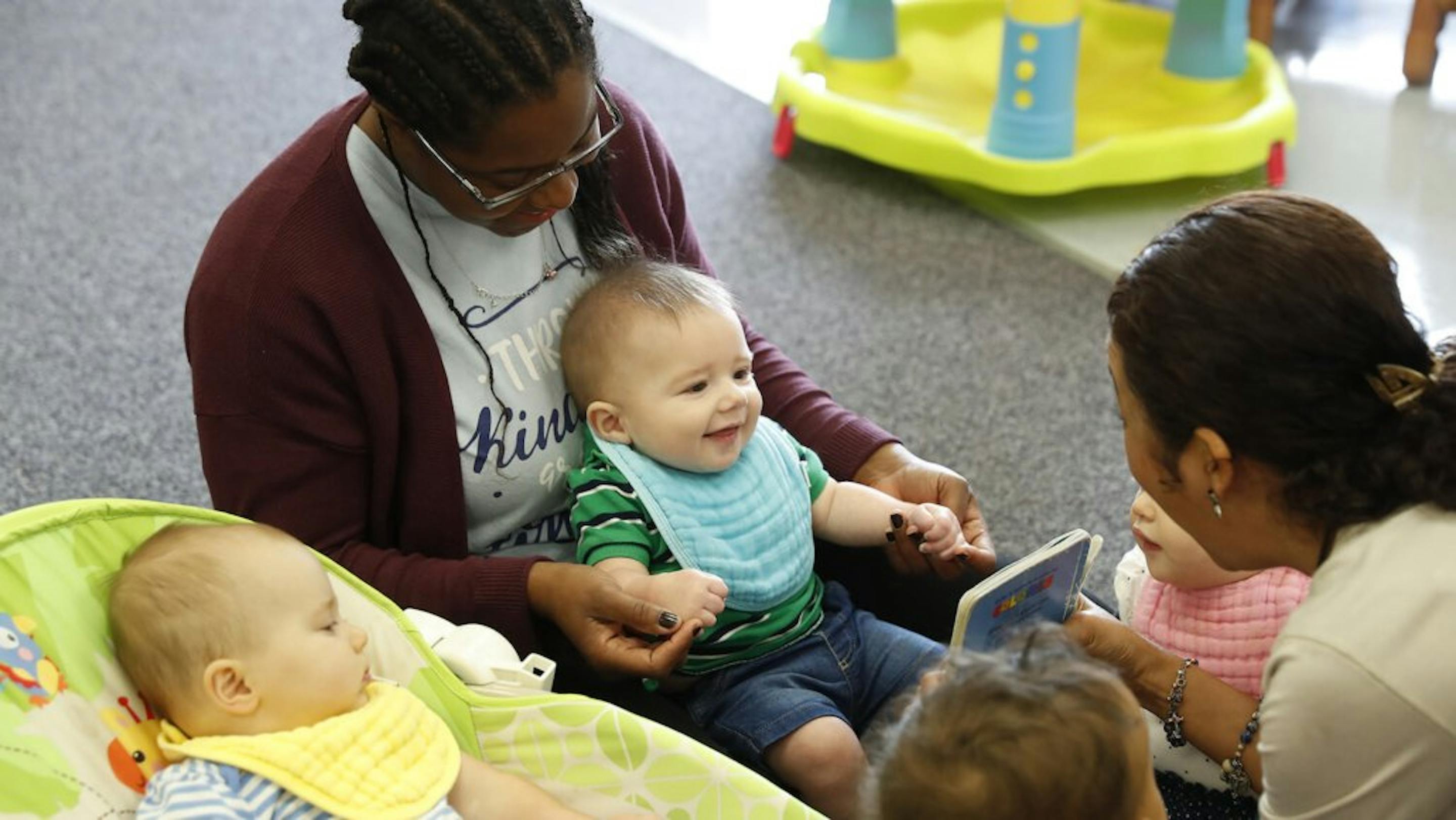 Person holding a child, another person interacting with children